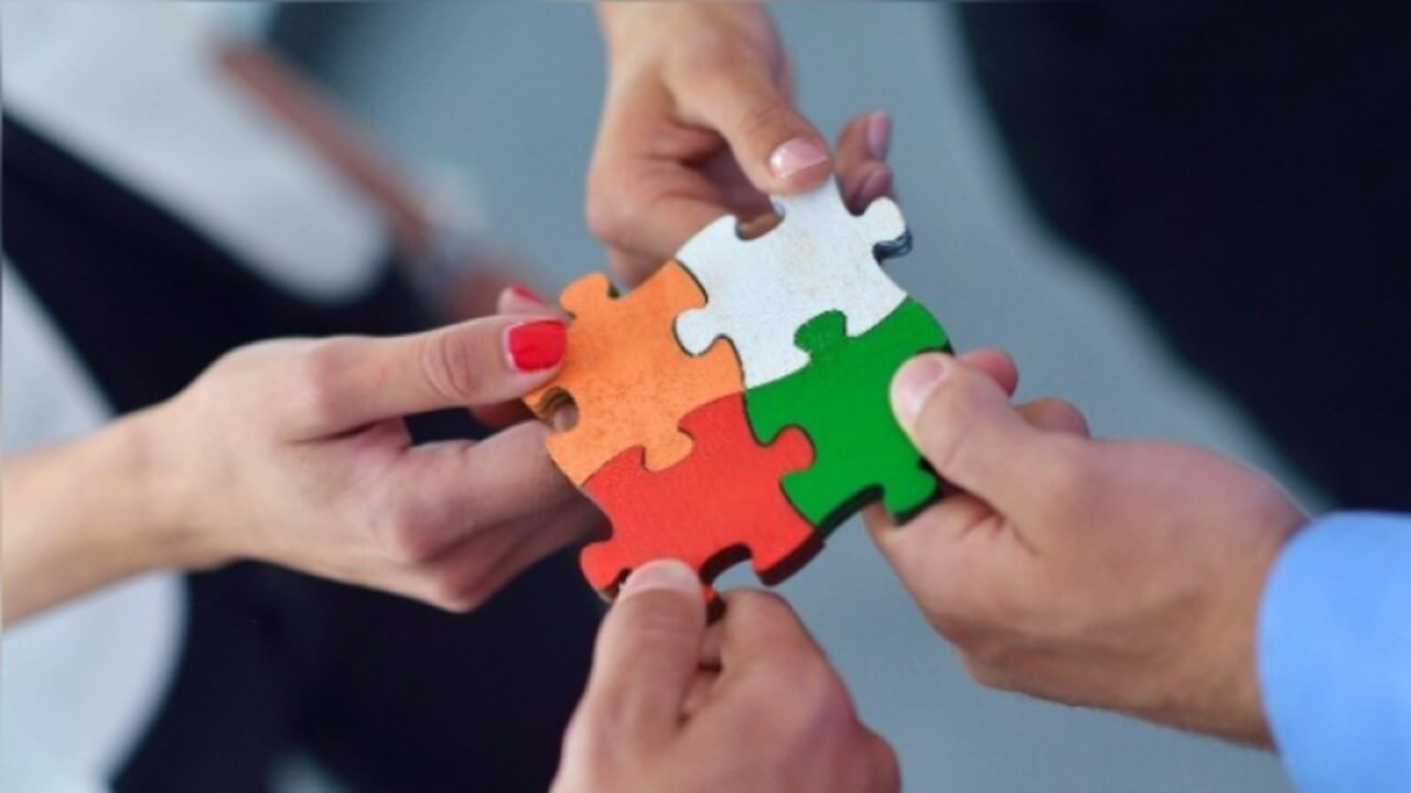 Cuatro personas con sus manos unen sus sinergias con la habilidades blandas para impulsar el trabajo en equipo